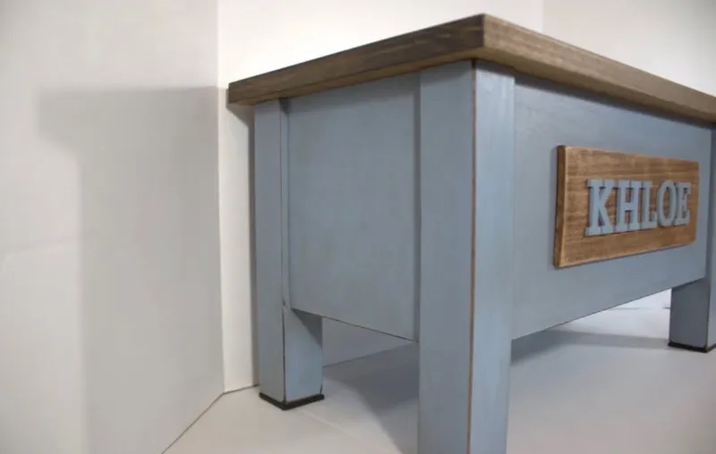 Opposite angle of the blue Khloe stand with its brown nameplate and square legs